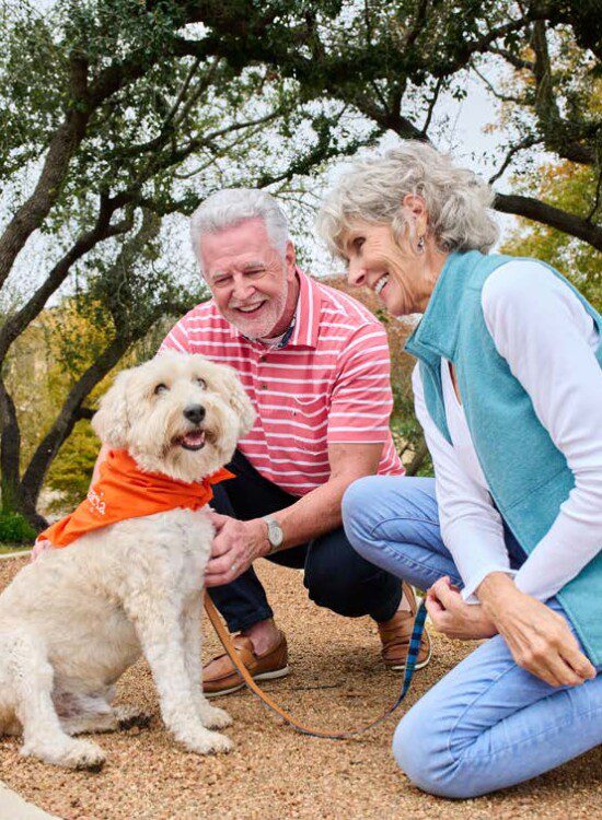 man and woman kneeling down with dog outside